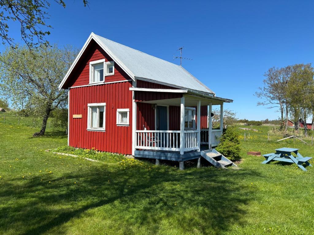a red house with a picnic table in a field at Klobbars Gästhem o Stugor in Kökar