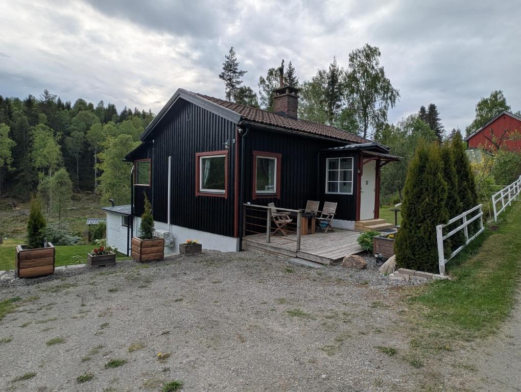 a black house with a porch and a deck at Hindås stuga in Hindås
