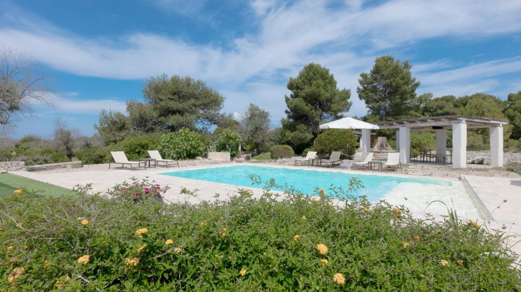 a swimming pool with chairs and a gazebo at Borgo del Sole Salento in Torre Vado