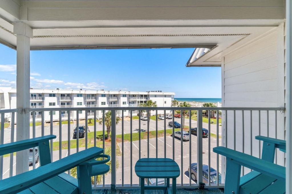a balcony with blue chairs and a view of a parking lot at Hotel condo features beach access shared pool - near town in Fort Morgan