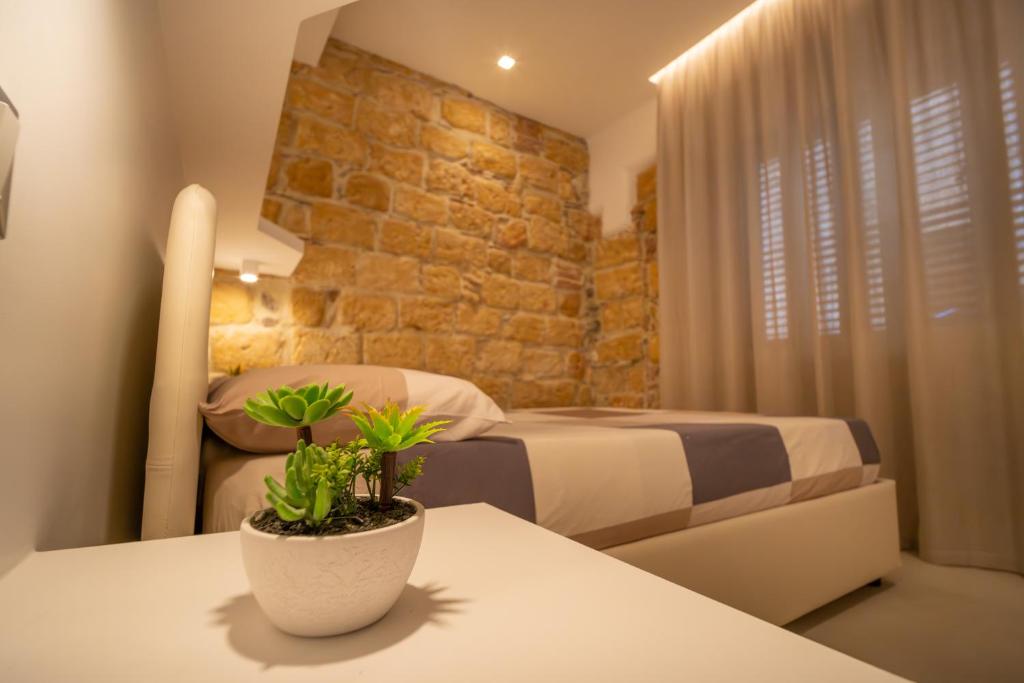 a bedroom with two beds and a table with a plant at DaiRa 103 Luxury Suite sulle Mura di Cefalù in Cefalù