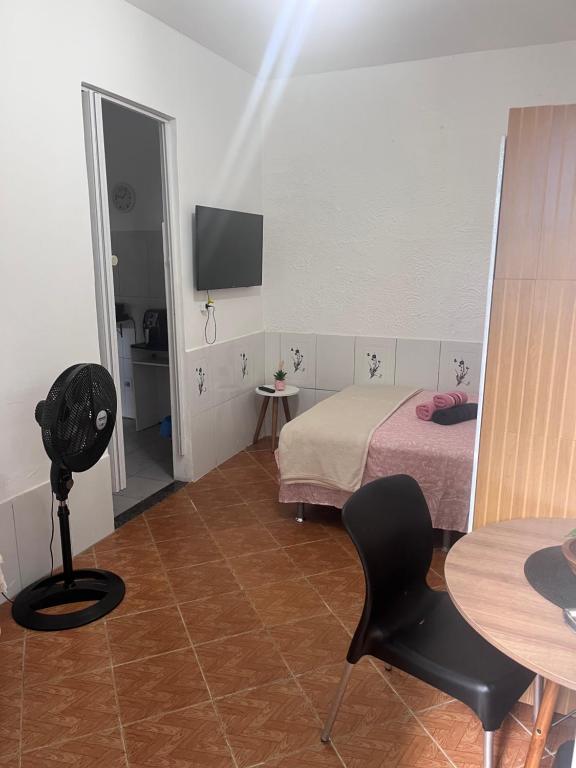 a room with a bed and a table and a chair at Kitnet aconchegante in Pedra de Guaratiba