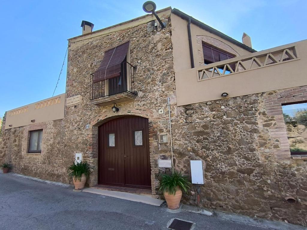 a stone building with a brown door and a balcony at L'Era de Can Ribes Tor in Tor