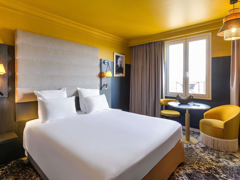 a hotel room with a large bed and a desk at Mercure Honfleur in Honfleur