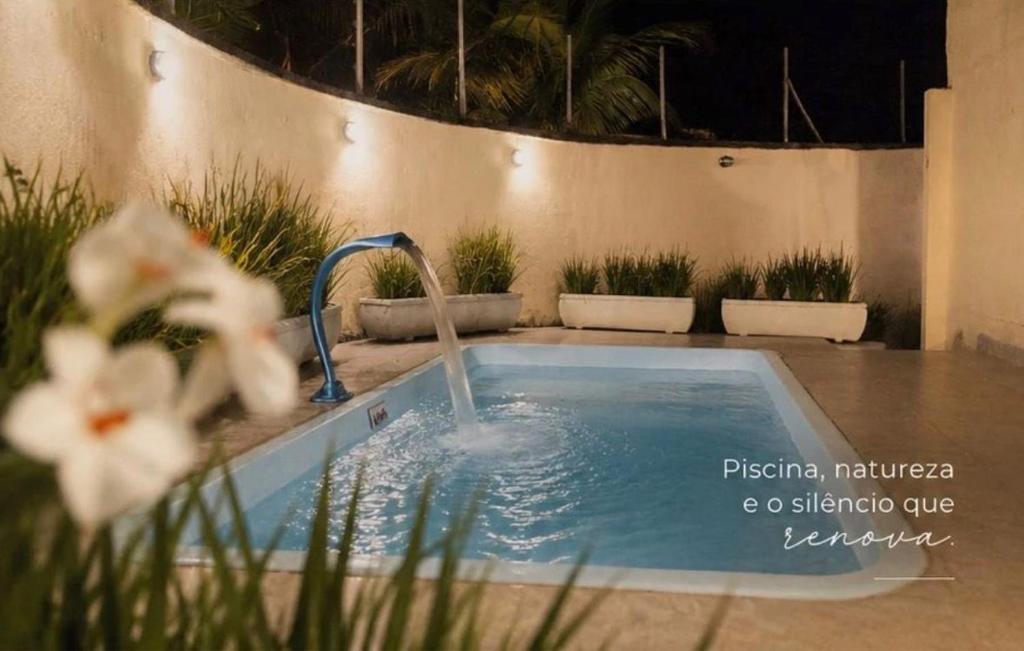 a swimming pool with a water fountain in a yard at Pousada Boutique Três Marias in Guarujá