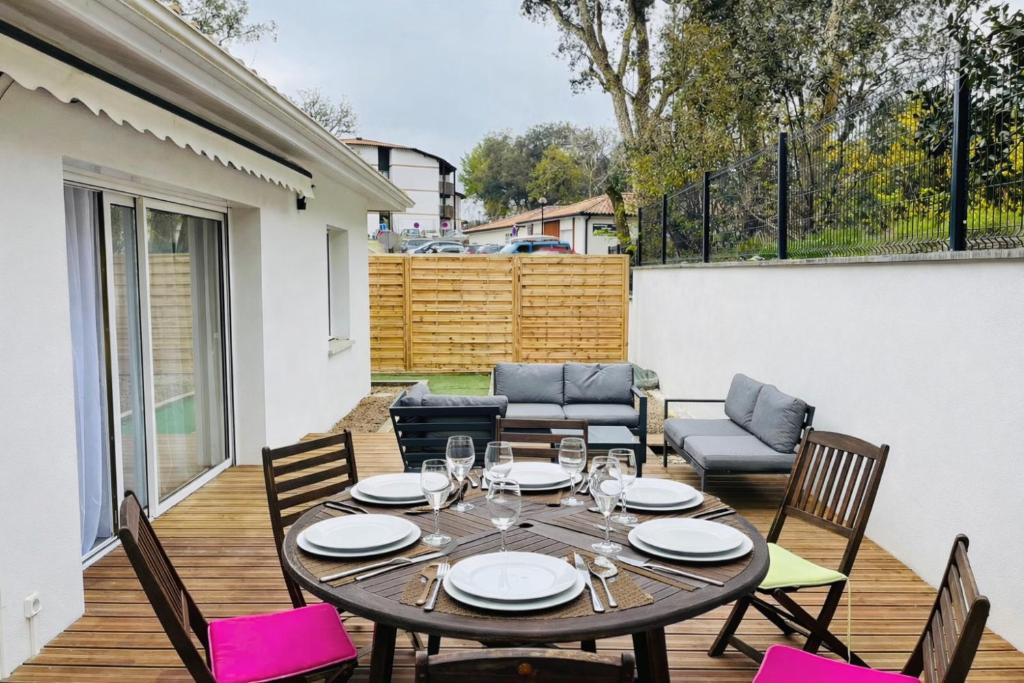 a dining table and chairs on a wooden deck at Charmante maison neuve proche Ocean in Léon