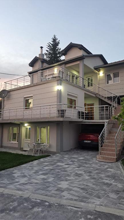 a large white house with a balcony and stairs at Vila Dunjić Prolom Banja in Prolomska Banja