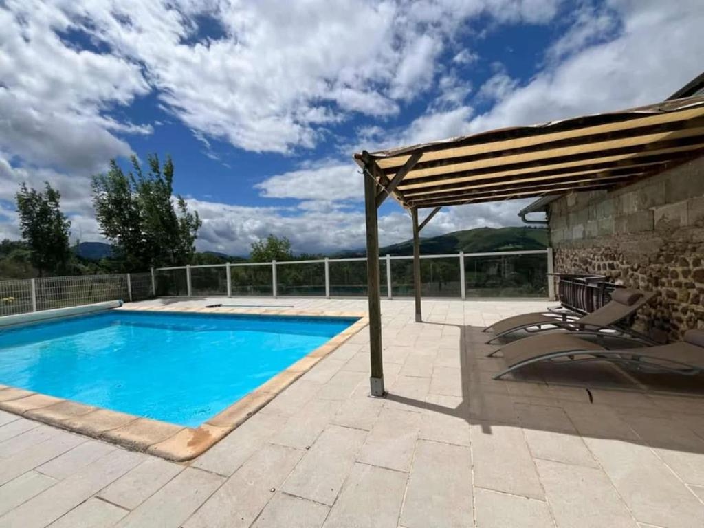 a swimming pool with an umbrella and chairs next to it at Le Gite Cazette in Ance