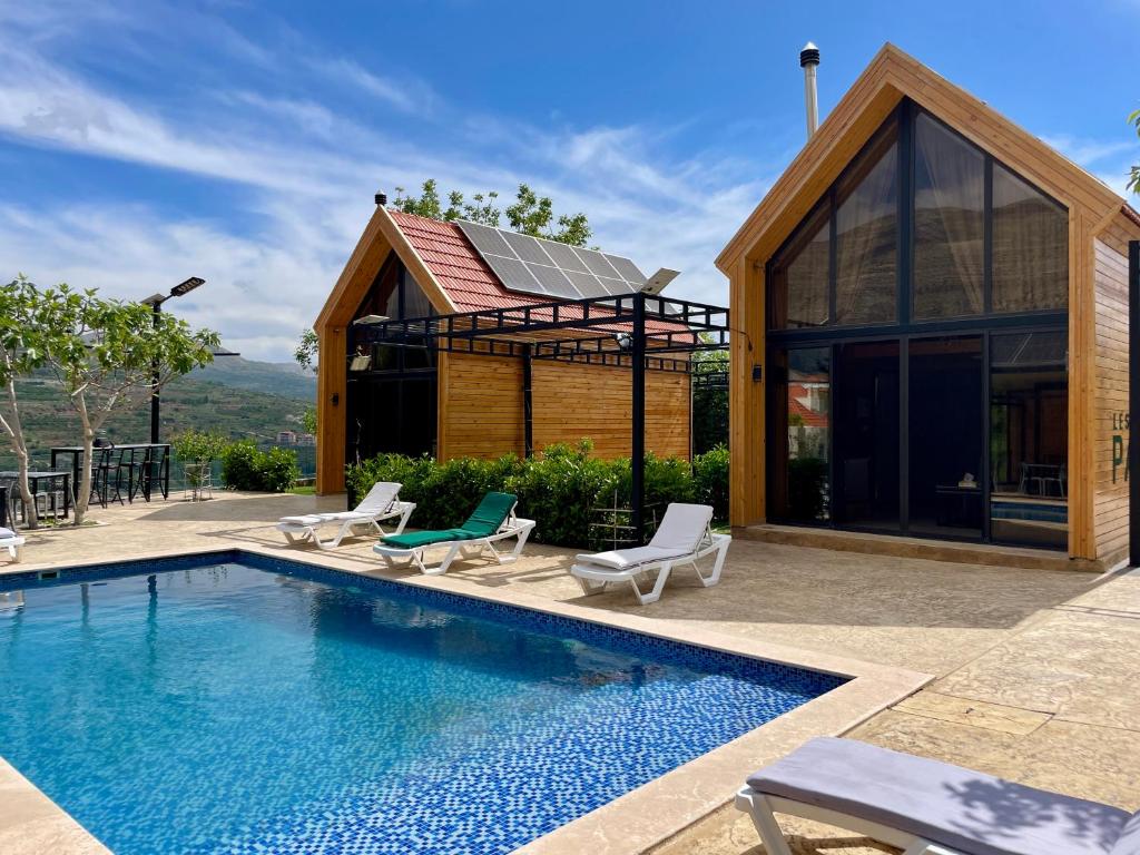 a pool with chairs and a house with a building at Les Pavillons D'Ehden in Ehden