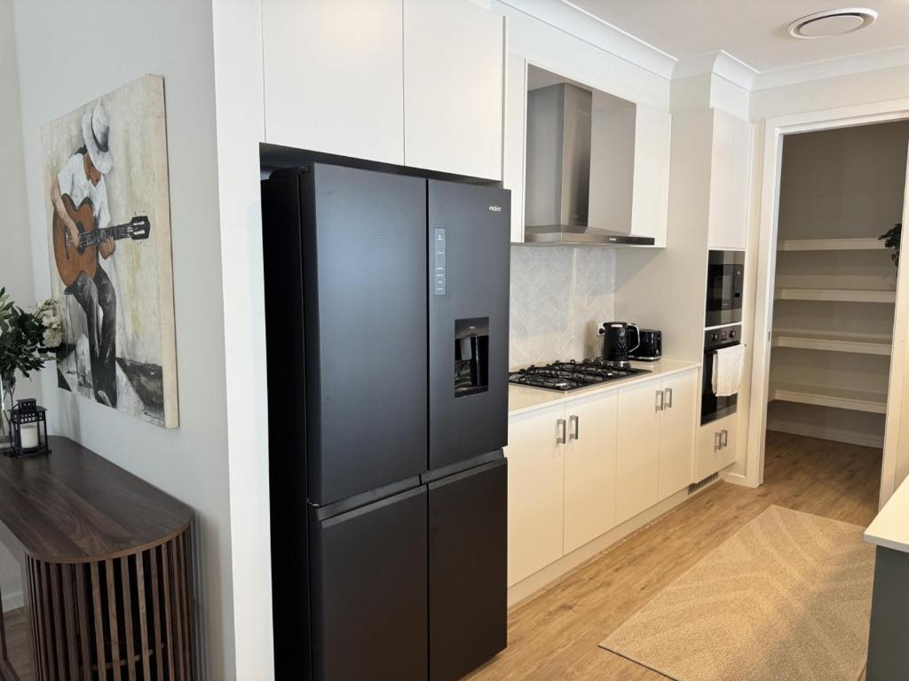 a kitchen with a black refrigerator in a room at Spacious New Home for 12 Guests in Campbelltown South