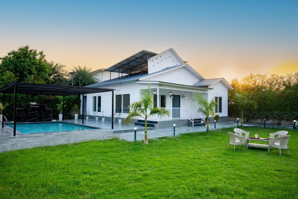 a white house with a yard and a pool at Luxury Haven Stay in Noida