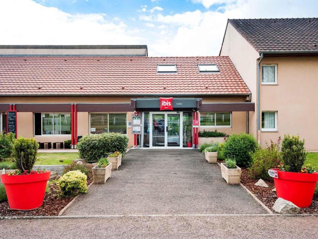 a building with red pots in front of it at ibis Avallon in Magny