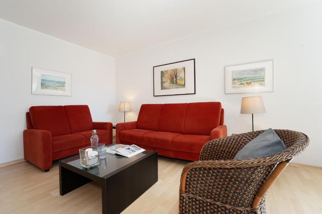 a living room with two red chairs and a coffee table at Gut Staberhof Staberholz in Staberdorf