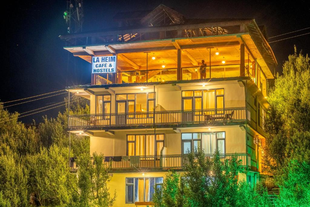 a building with a sign on the side of it at La Heim Hostels in Manāli