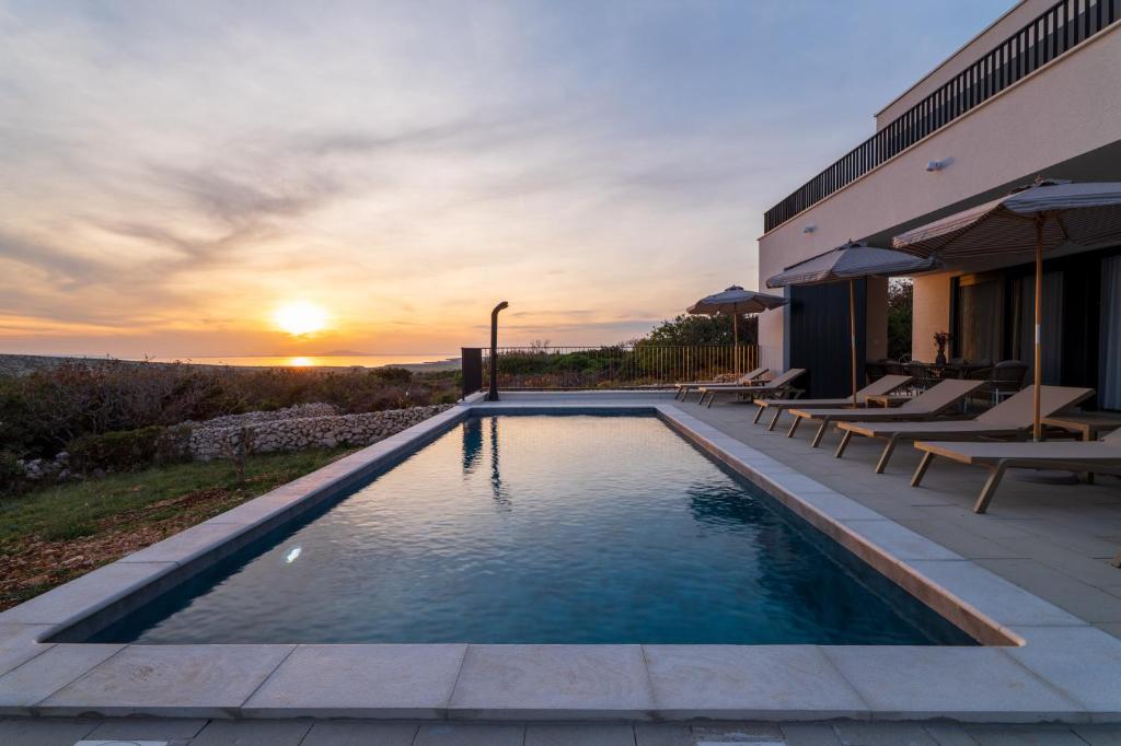 a swimming pool in front of a house with the sunset at Villa Carbonia in Kolan