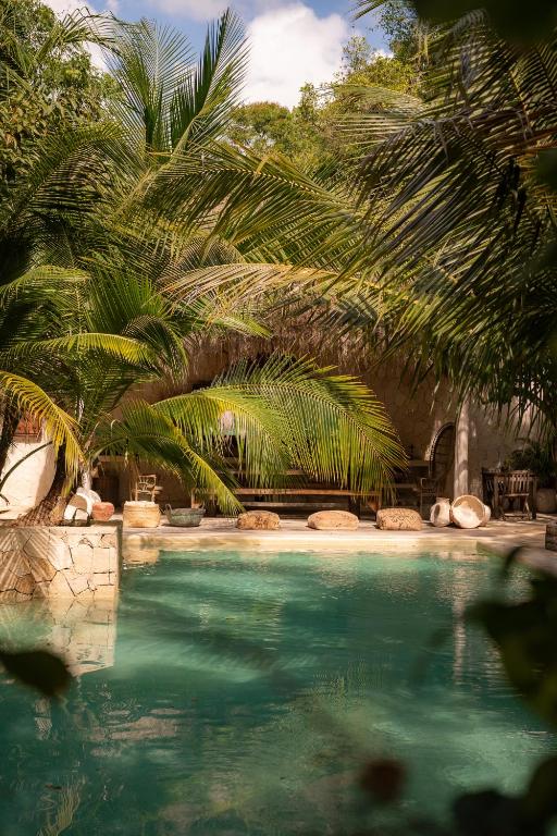 a swimming pool with palm trees in the background at Una Vida in Tulum
