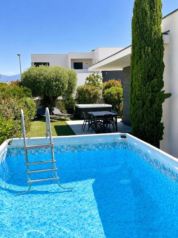 a swimming pool with two chairs and a table at Villa Dolce Vida proche golf, lac, plage et Collioure in Villeneuve-de-la-Raho