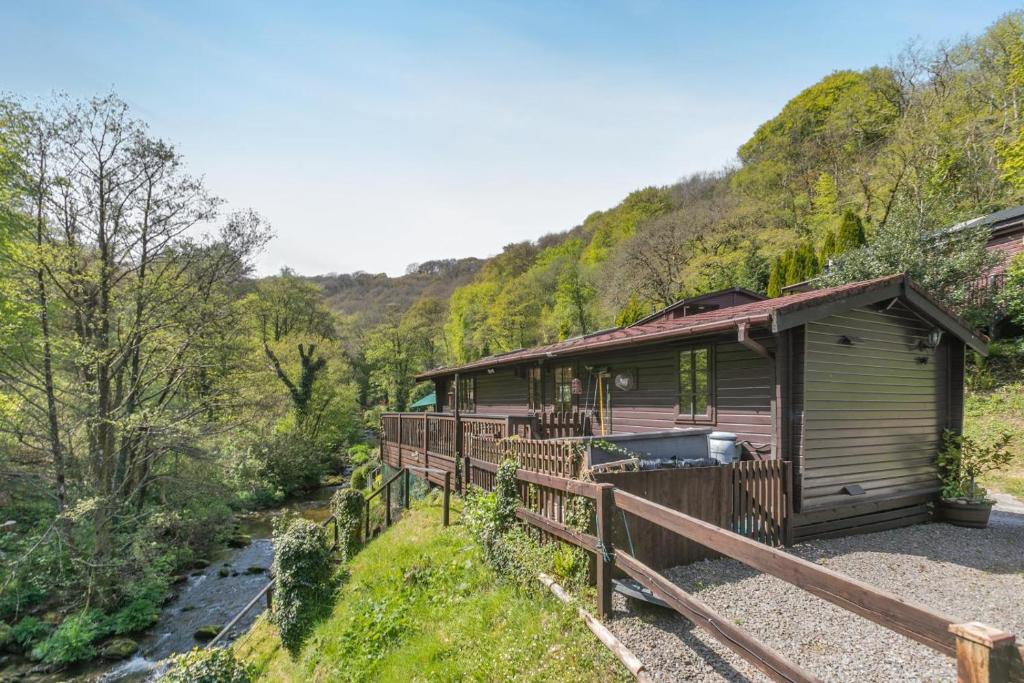 a cabin in the woods with a fence around it at 2 Bed in Lynton oc-riverl in Lynmouth