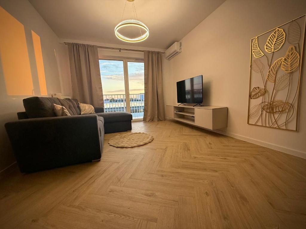 a living room with a couch and a television at Kaszmirowy Apartament in Mrągowo