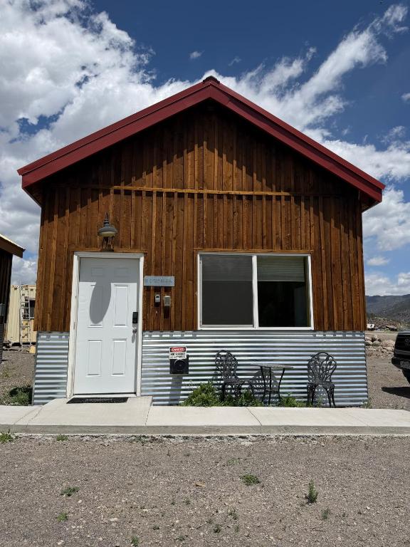 a small house with a white door and two chairs at The Trail Head in South Fork