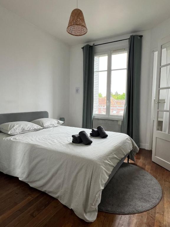 a bedroom with a bed with two black towels on it at Le Clair Bellifontain in Fontainebleau