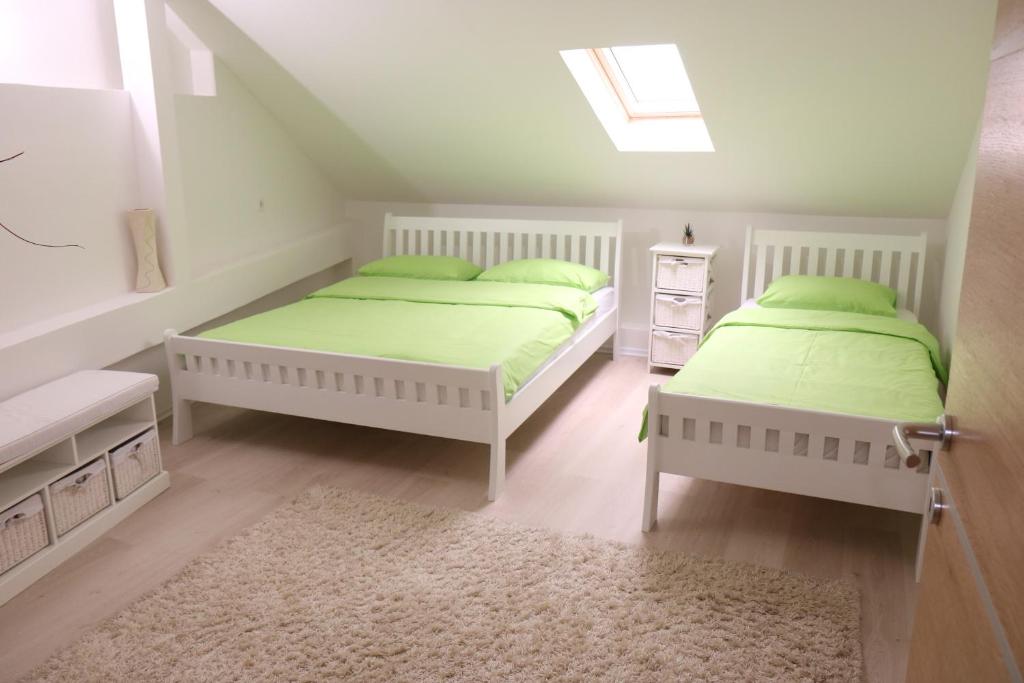2 camas en una habitación blanca con sábanas verdes en Apartment Vremeplov, en Travnik