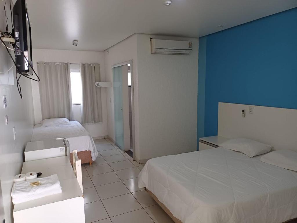 a hotel room with two beds and a blue wall at Hotel Imperador in Jaraguá