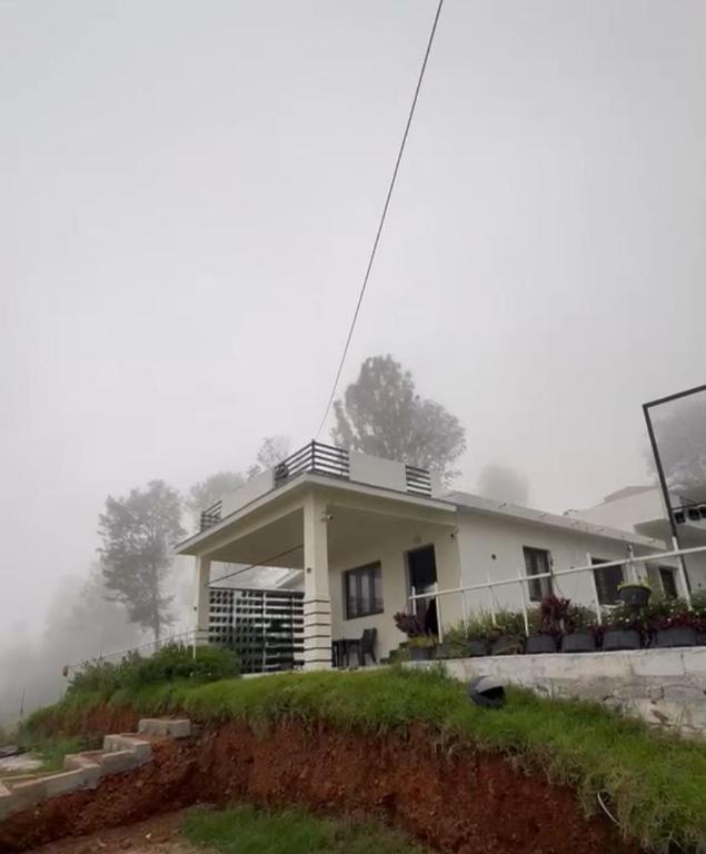 a house on a hill in the fog at The White Haven Kotagiri in Kotagiri