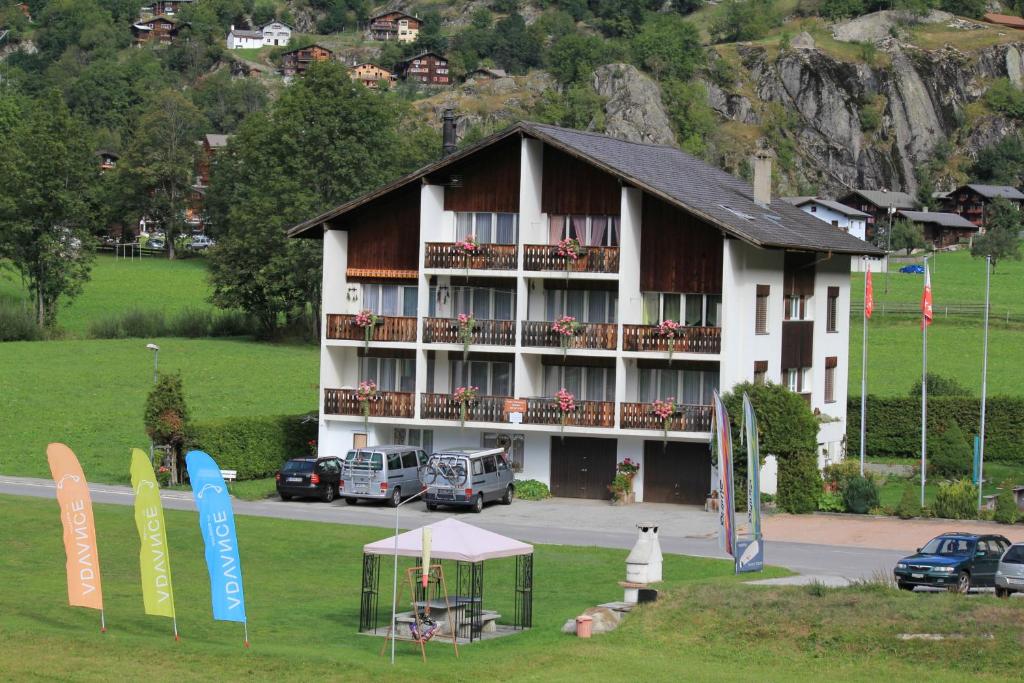 a large building with cars parked in front of it at Casa Yolanda Fiesch-Fieschertal, in der Aletsch Arena in Fiesch