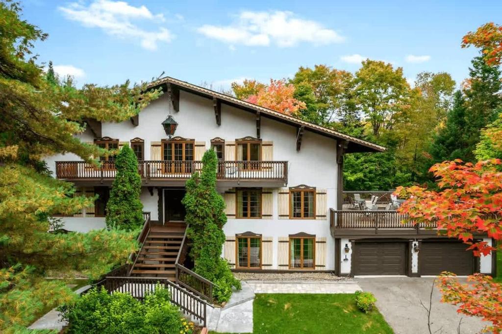 a large white house with a balcony at Genteman Manor Private Indoor Pool Sauna & Lake in Sainte-Agathe-des-Monts