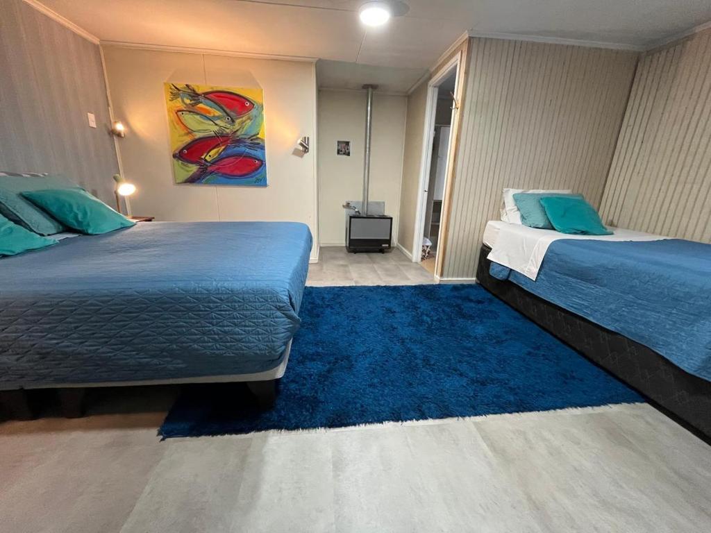 a bedroom with two beds and a blue rug at Caiquén Cabaña Punta Arenas in El Cerrillo