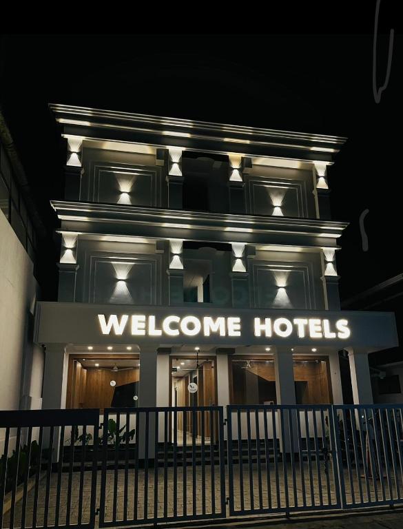 a building with a welcome hotel sign at night at Welcome Hotels in Trichūr