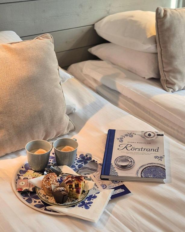 a tray of food and two cups of coffee on a bed at Hotell Rådhuset in Lidköping