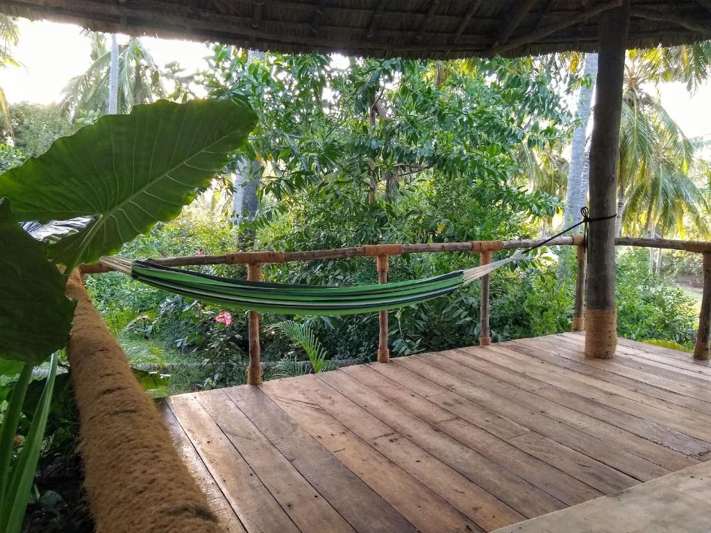 a hammock on a wooden deck with trees at LalaMafia Bungalow in Utende