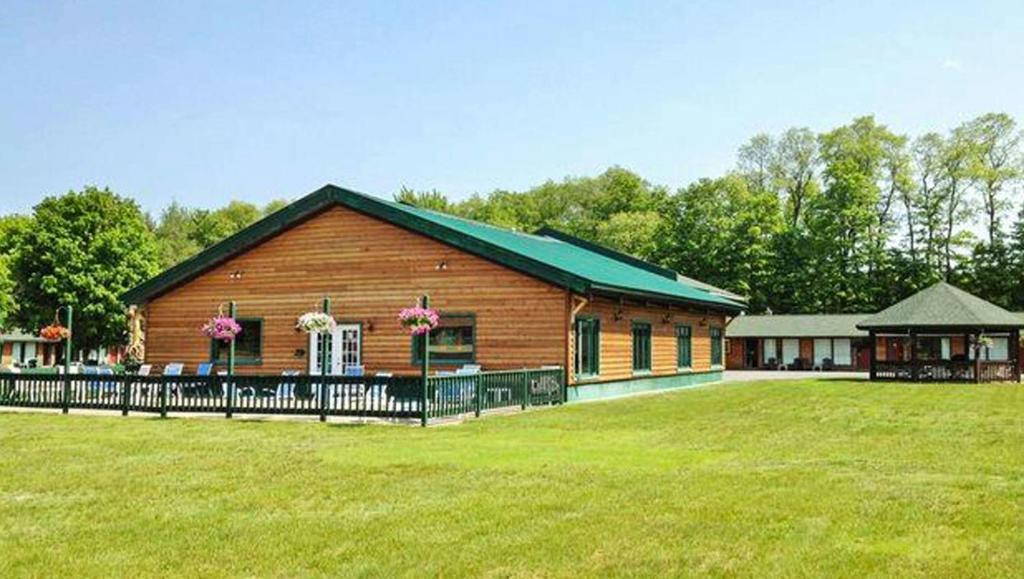 a wooden building with a fence in front of a field at Adirondack Lodge Old Forge in Old Forge