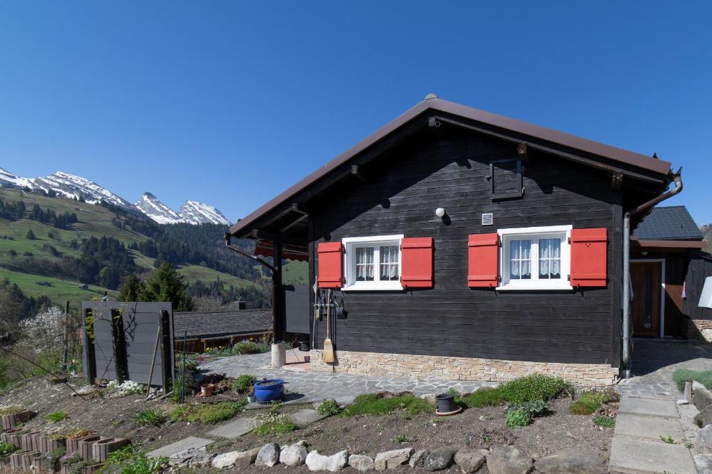 a black and red house with red shutters at Bergpanorama in Wildhaus