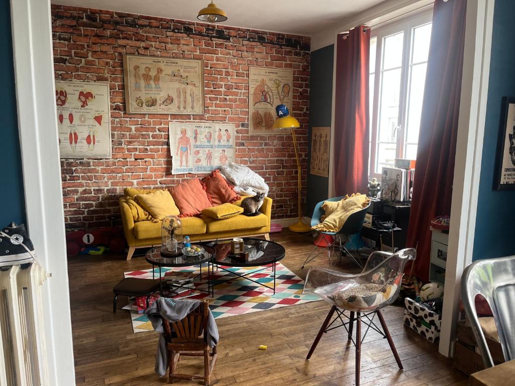a living room with a yellow couch and a brick wall at Le5 Brest in Brest