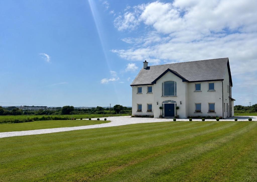 a white house on a large grassy field at Eastbury House near Garryvoe Hotel & Ballymaloe House in Cork