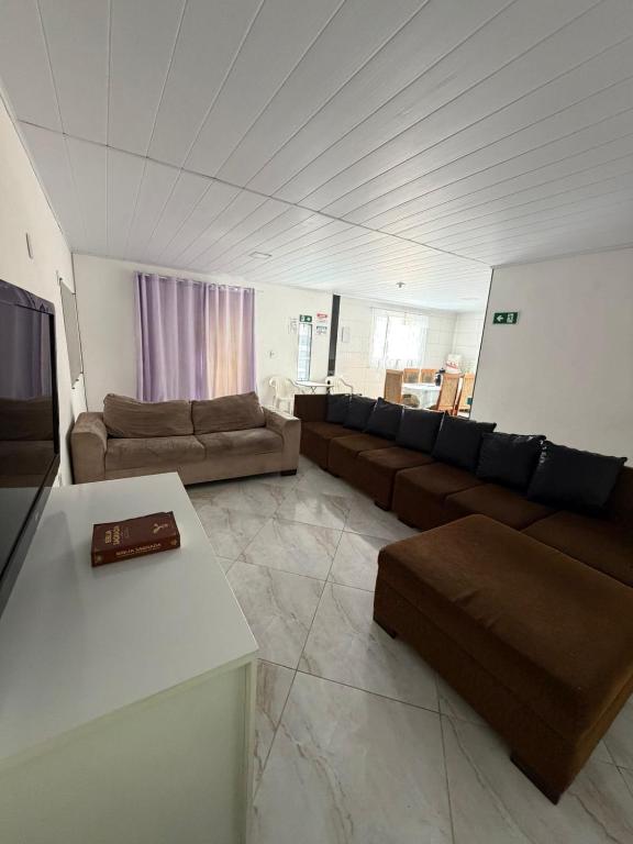 a large living room with couches and a tv at Quarto privado simples para o público masculino em acomodação compartilhada in Serra