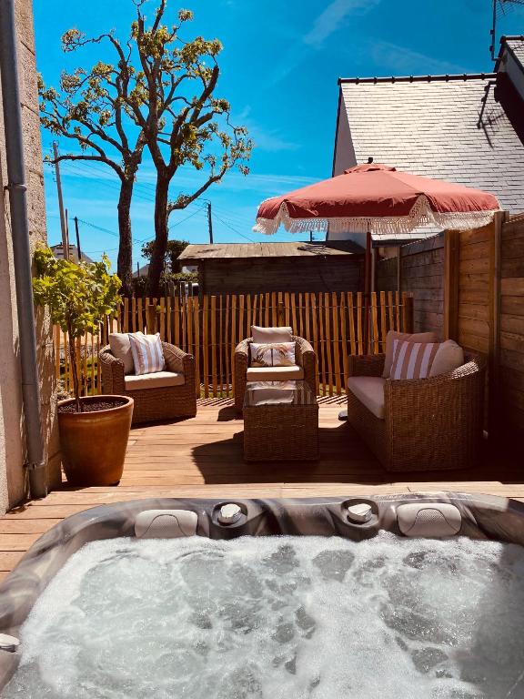 a hot tub on a deck with chairs and an umbrella at LES POIS SONT ROZ in Perros-Guirec