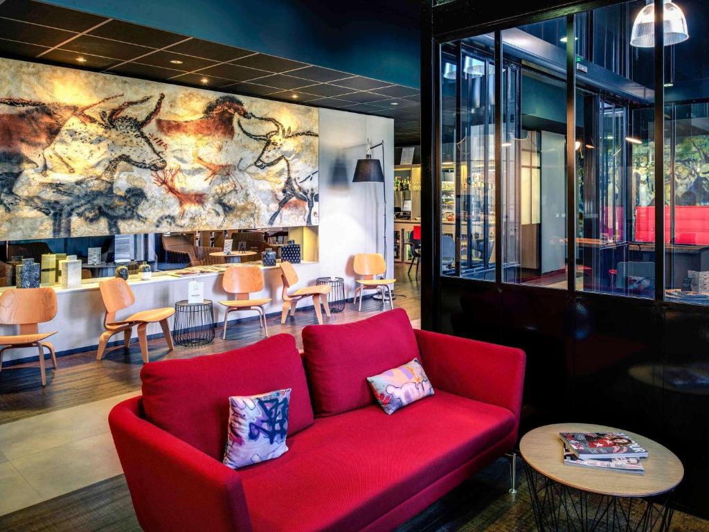 a red couch in a restaurant with a bar at Mercure Périgueux Centre Historique in Périgueux