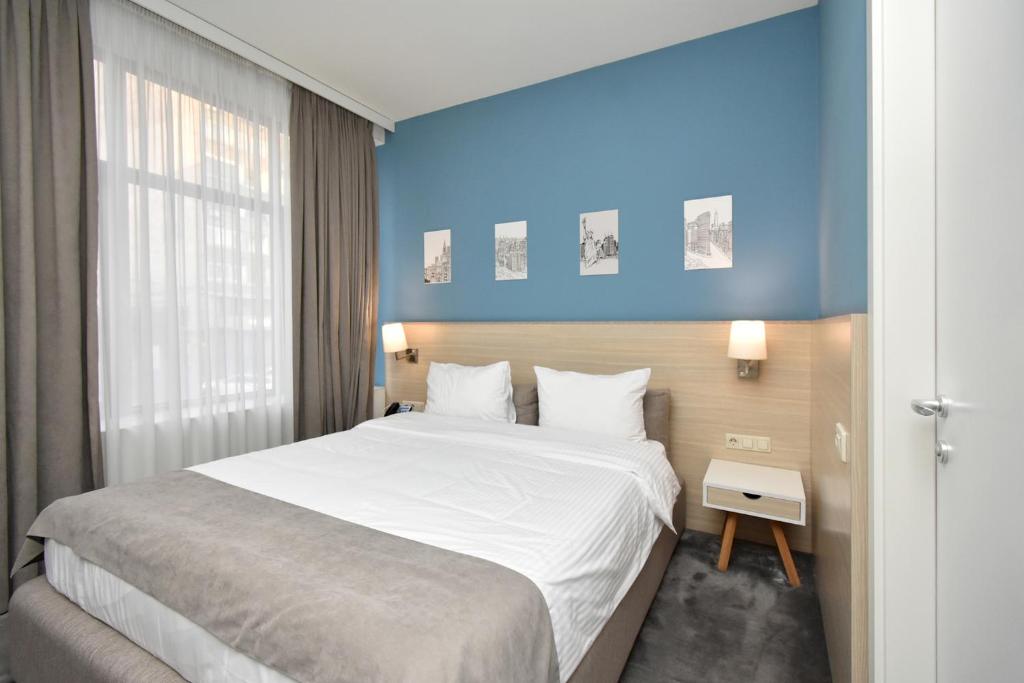 a bedroom with a large bed and a blue wall at In City Hotel in Yerevan