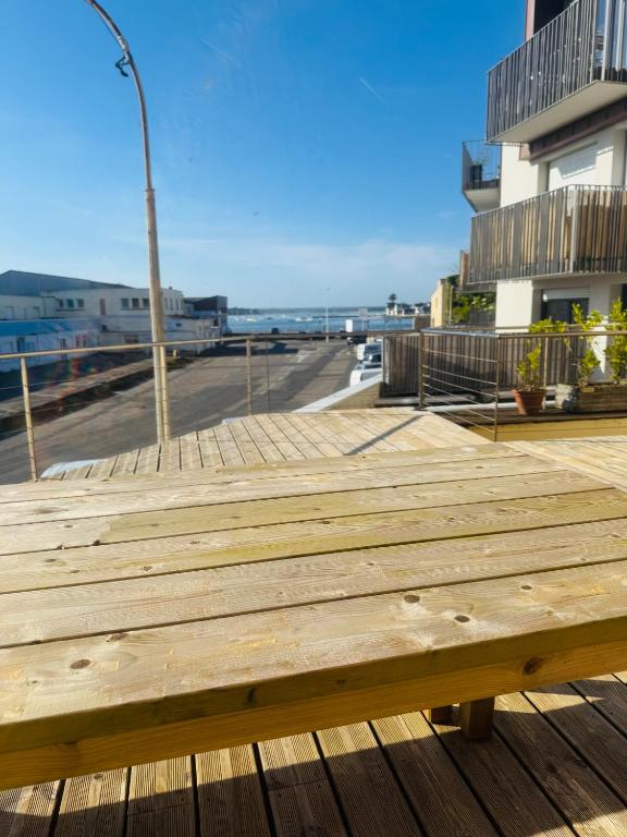 a wooden bench on a boardwalk near a street at Brõcean - Studio with sea view - in Loctudy