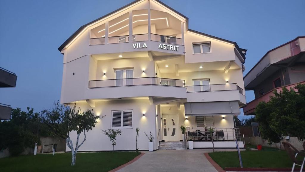 a white building with a sign on it at Vila Astrit in Fier