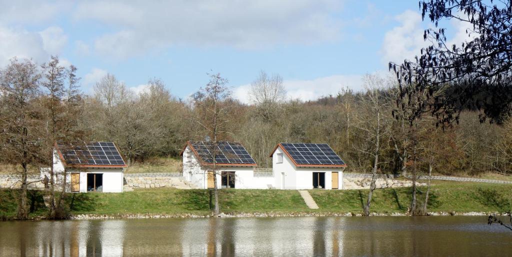 two houses with solar panels on their roofs next to a lake at Ferienhäuser Ilsensee Schillingsfürst in Schillingsfürst
