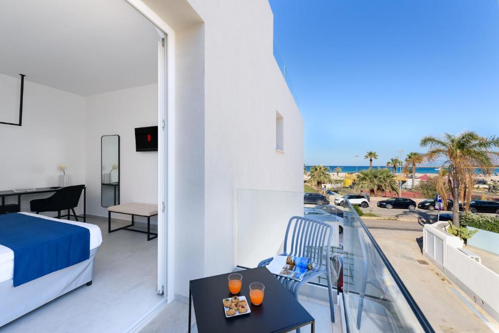a bedroom with a balcony with a bed and a table at Sea View Hotel Fronte Mare in San Vito lo Capo