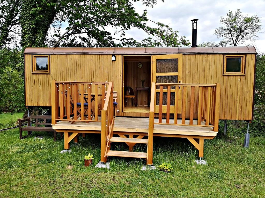 a wooden cabin with a deck and two chairs at Maringotka Rozálka in Dlouhá Stropnice