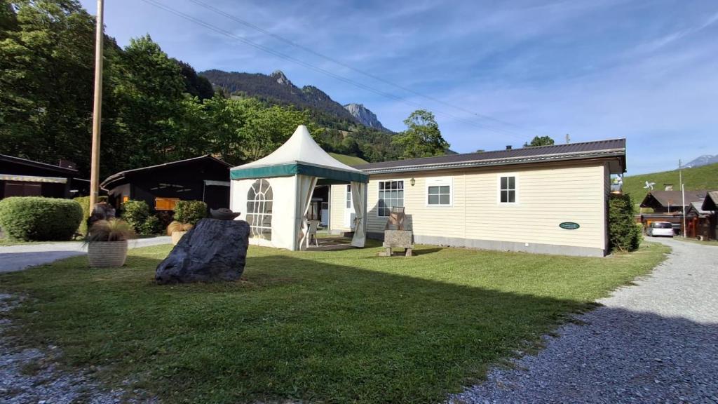 ein kleines weißes Gebäude mit einem großen Stein im Gras in der Unterkunft Mobilehome in Weissenburg