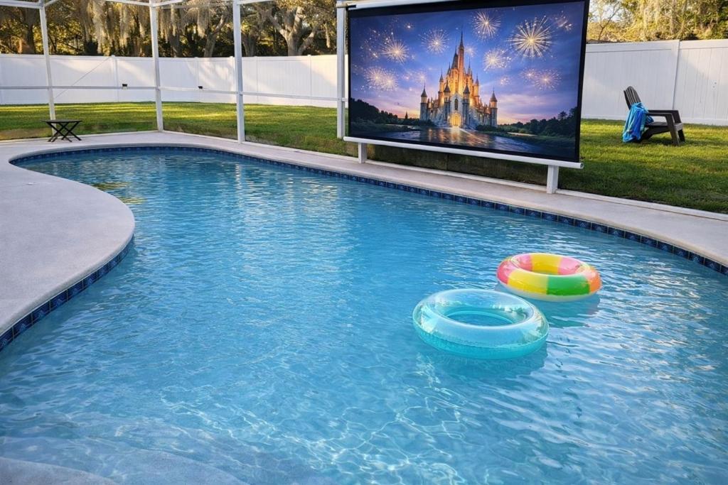 a swimming pool with a tv in the background at Amazing Star Wars Villa - Theater, Full Arcade & Private Pool, 5BR Near Disney in Orlando