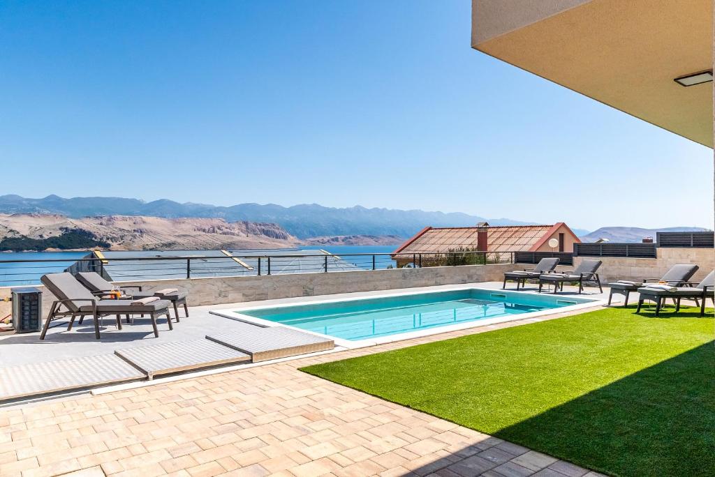 a swimming pool with chairs and a table and grass at Villa Serenity Pag Sv. Marko in Pag
